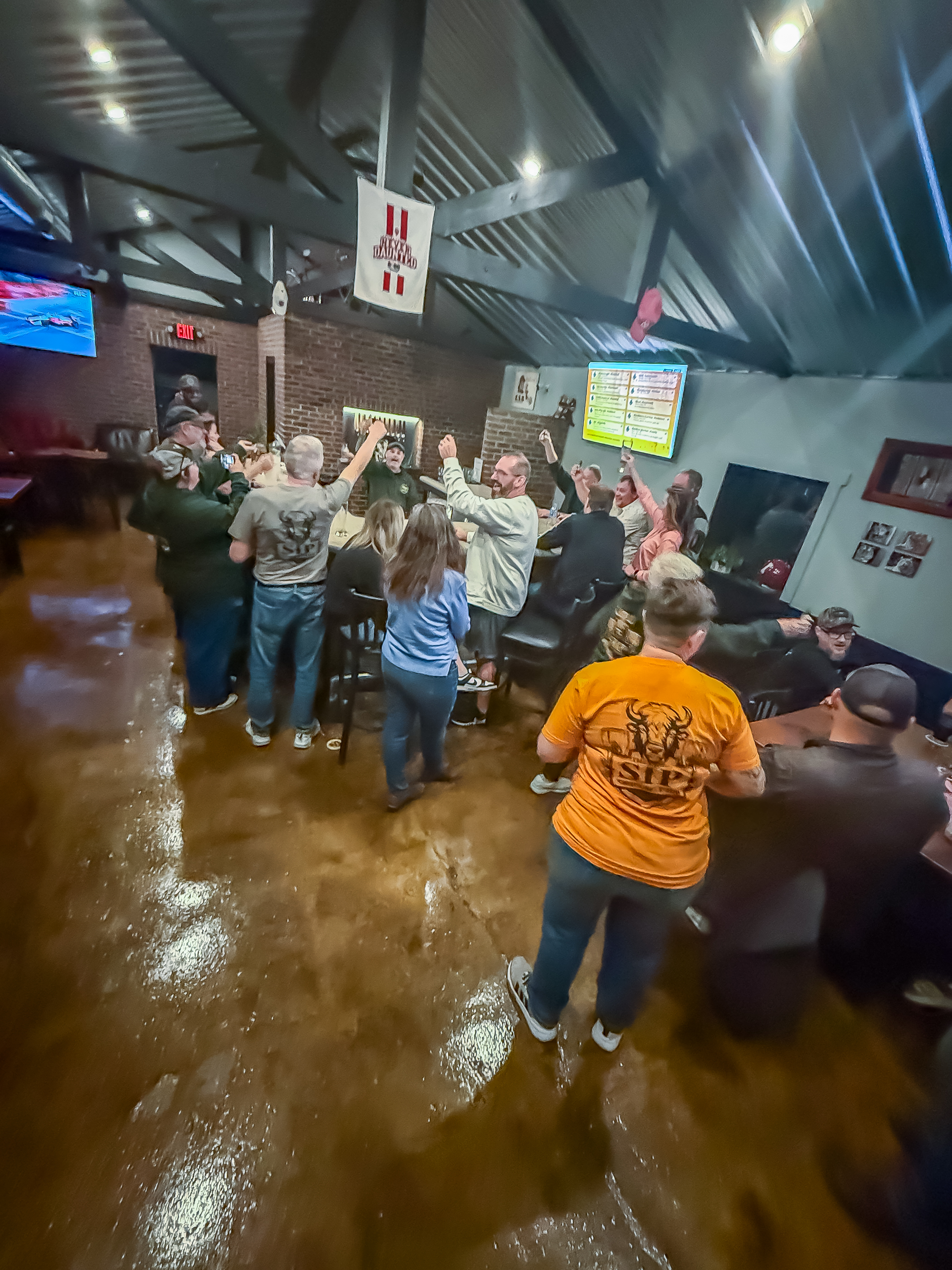 Guests raising glasses in a celebratory craft beer toast inside The Sip Craft Beer Pub