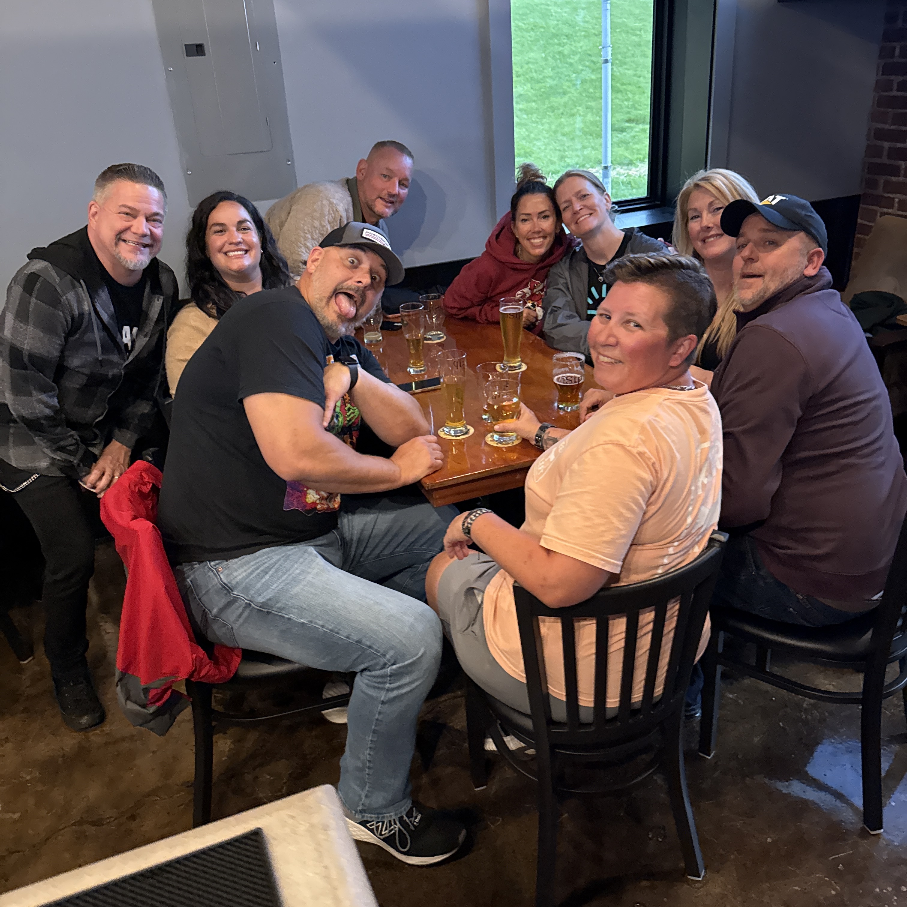 Friends smiling around a table with craft beer glasses at The Sip Craft Beer Pub