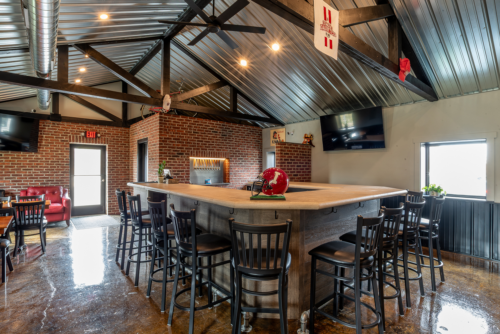 Interior of The Sip Craft Beer Pub showing the bar, tables, exposed beams, and craft beer tap wall in Bloomington, Indiana