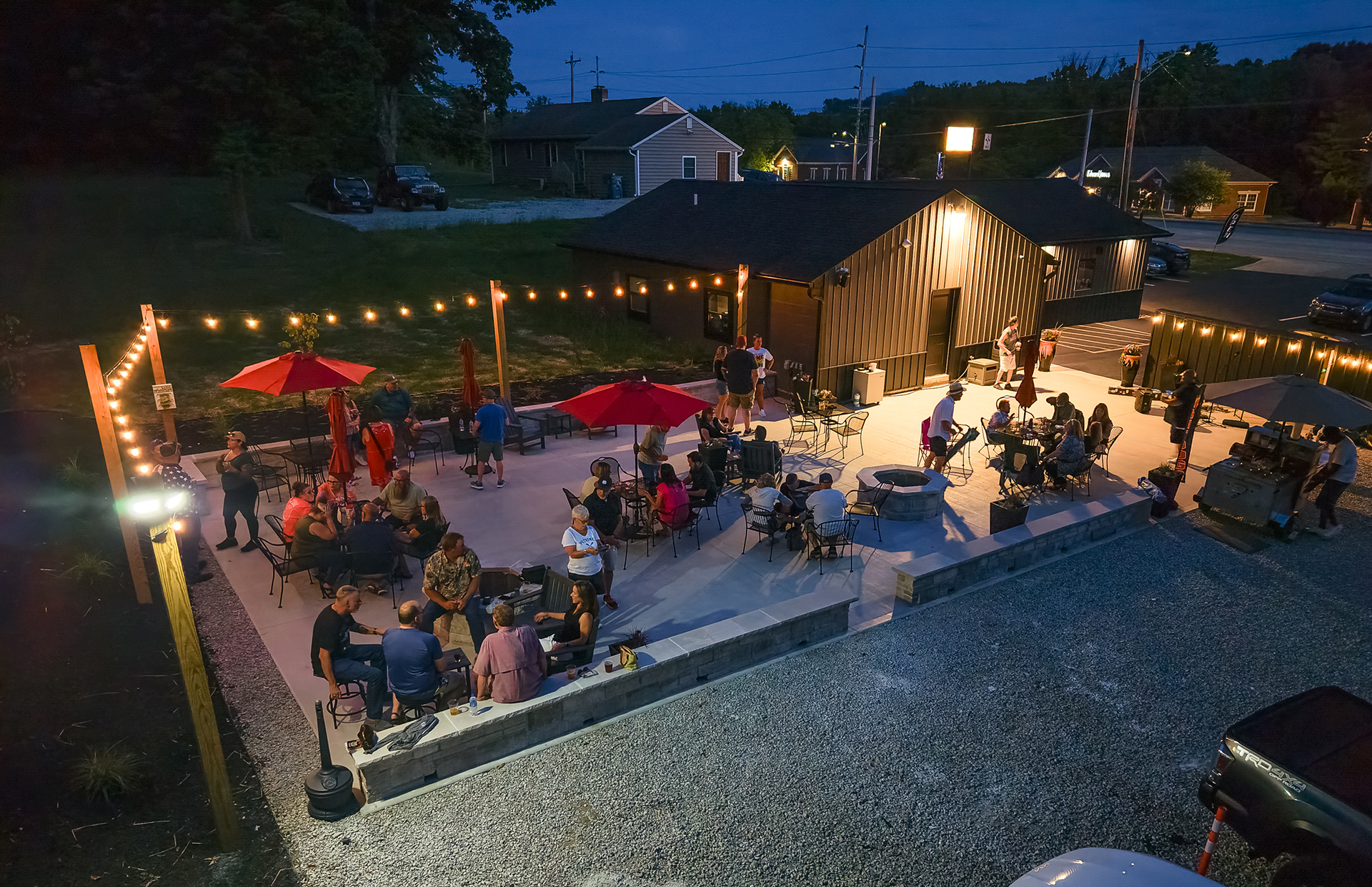 Guests enjoying the illuminated patio and fire pits at The Sip Craft Beer Pub in the evening