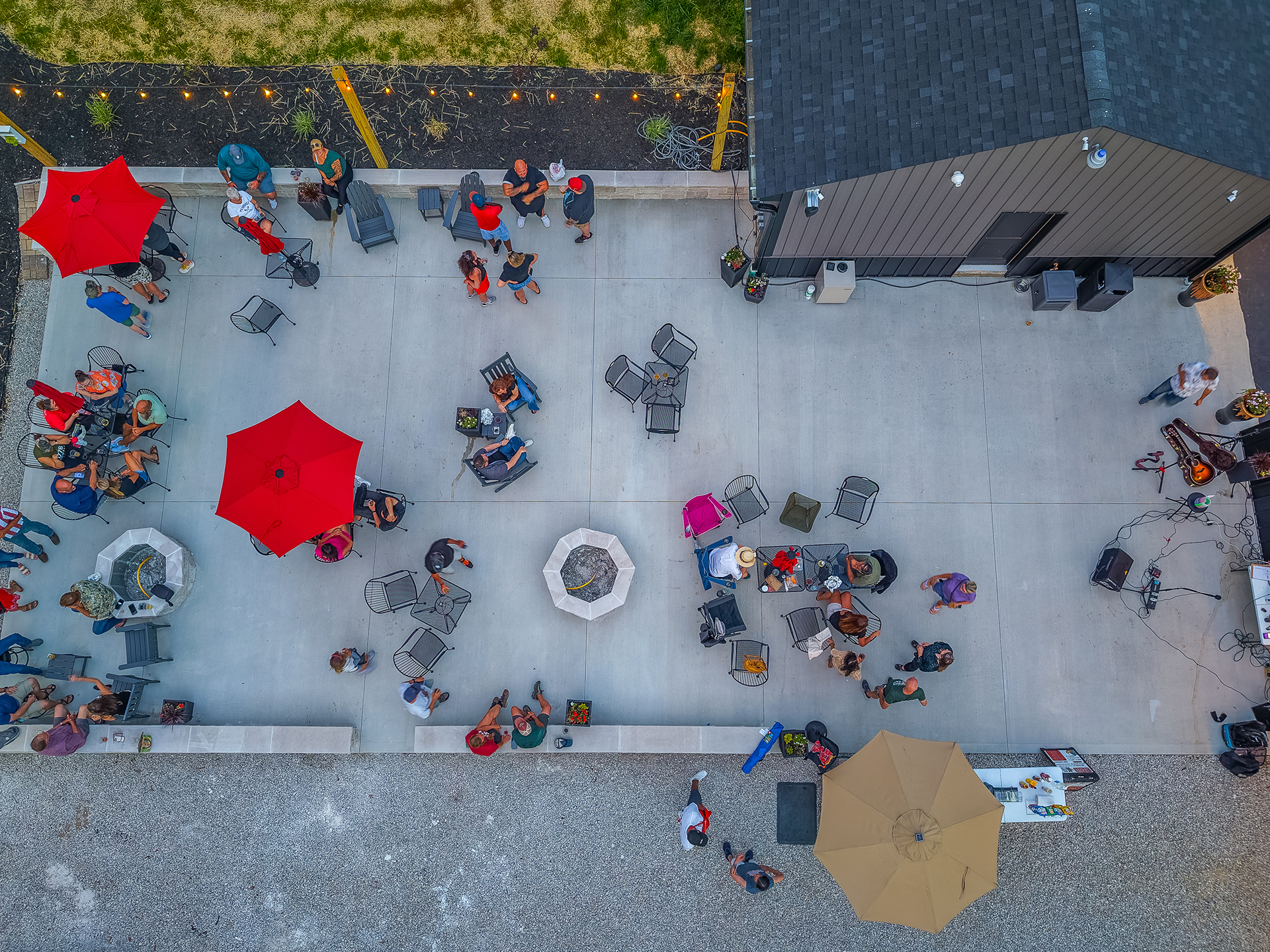 Overhead aerial view of The Sip patio during an event with guests, tables, fire pits, and live music equipment